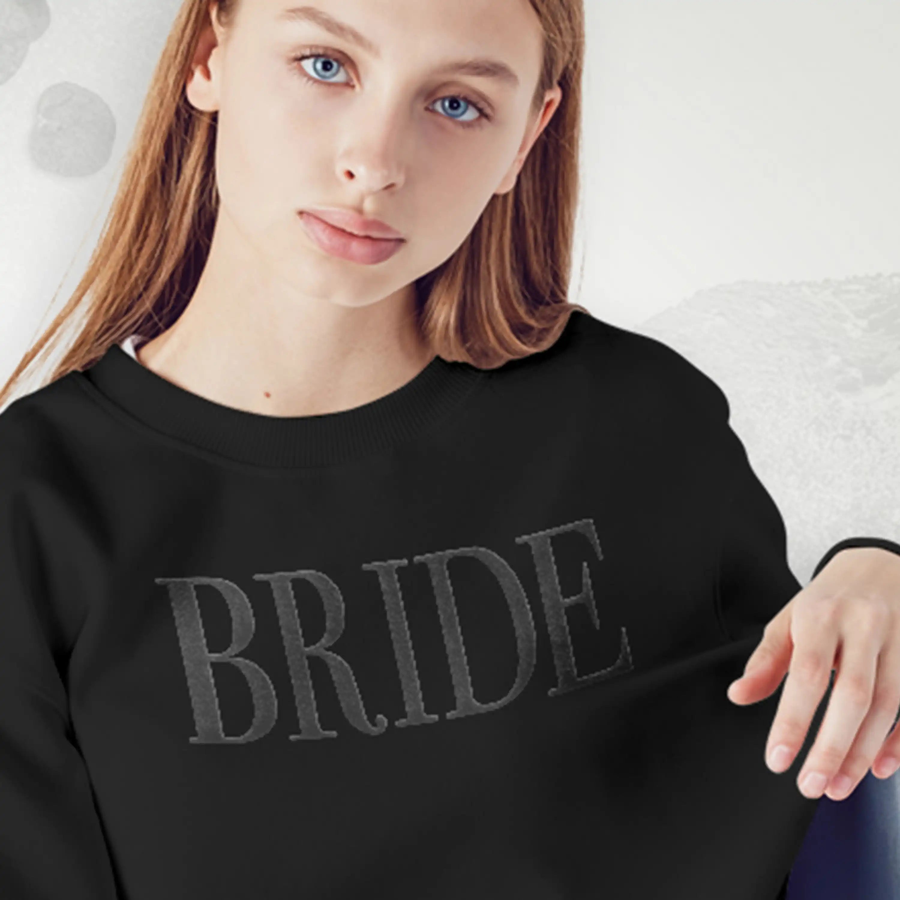 Person wearing a black sweatshirt with 'BRIDE' printed on it against a light background