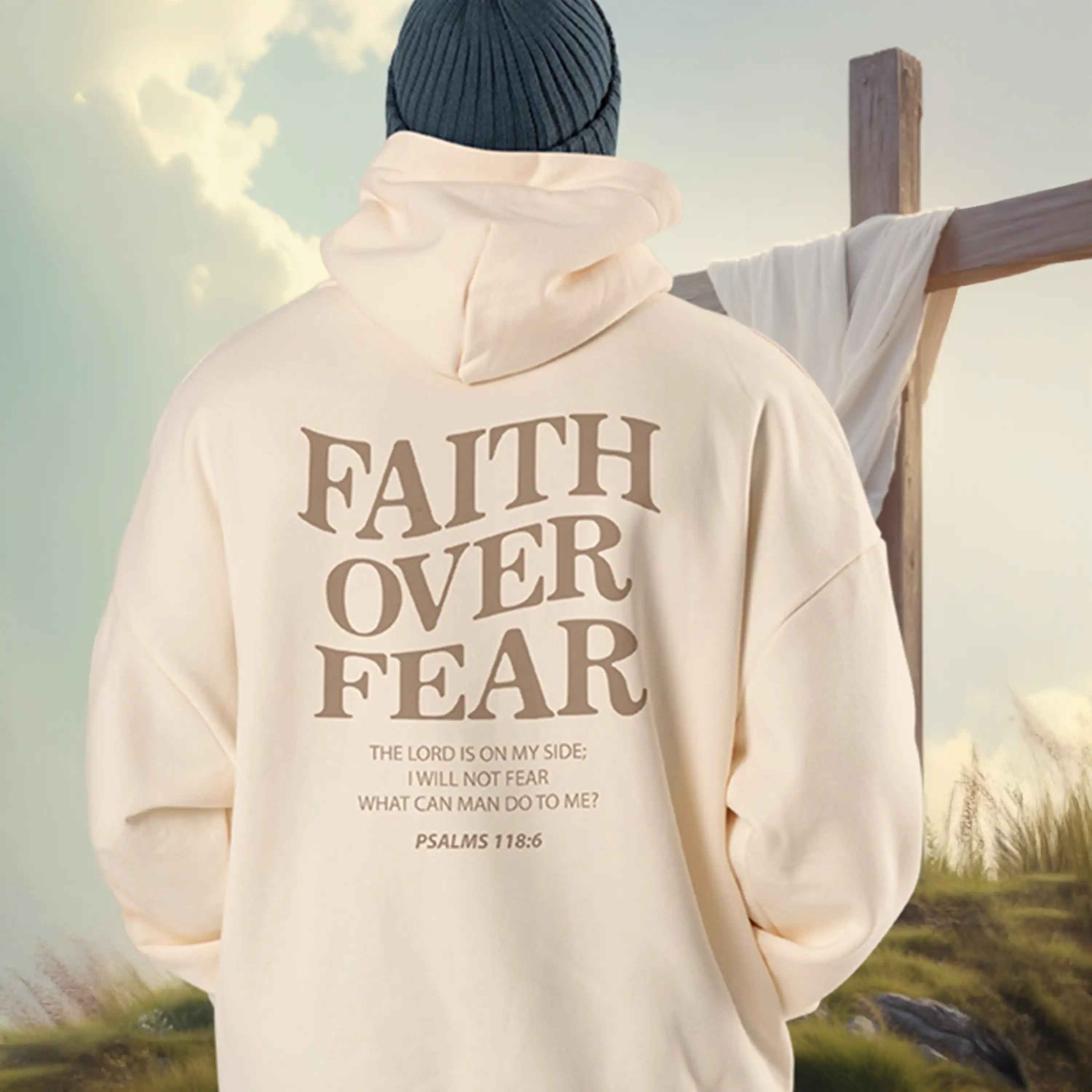 Person wearing a hoodie with 'Faith Over Fear' text in a scenic outdoor setting
